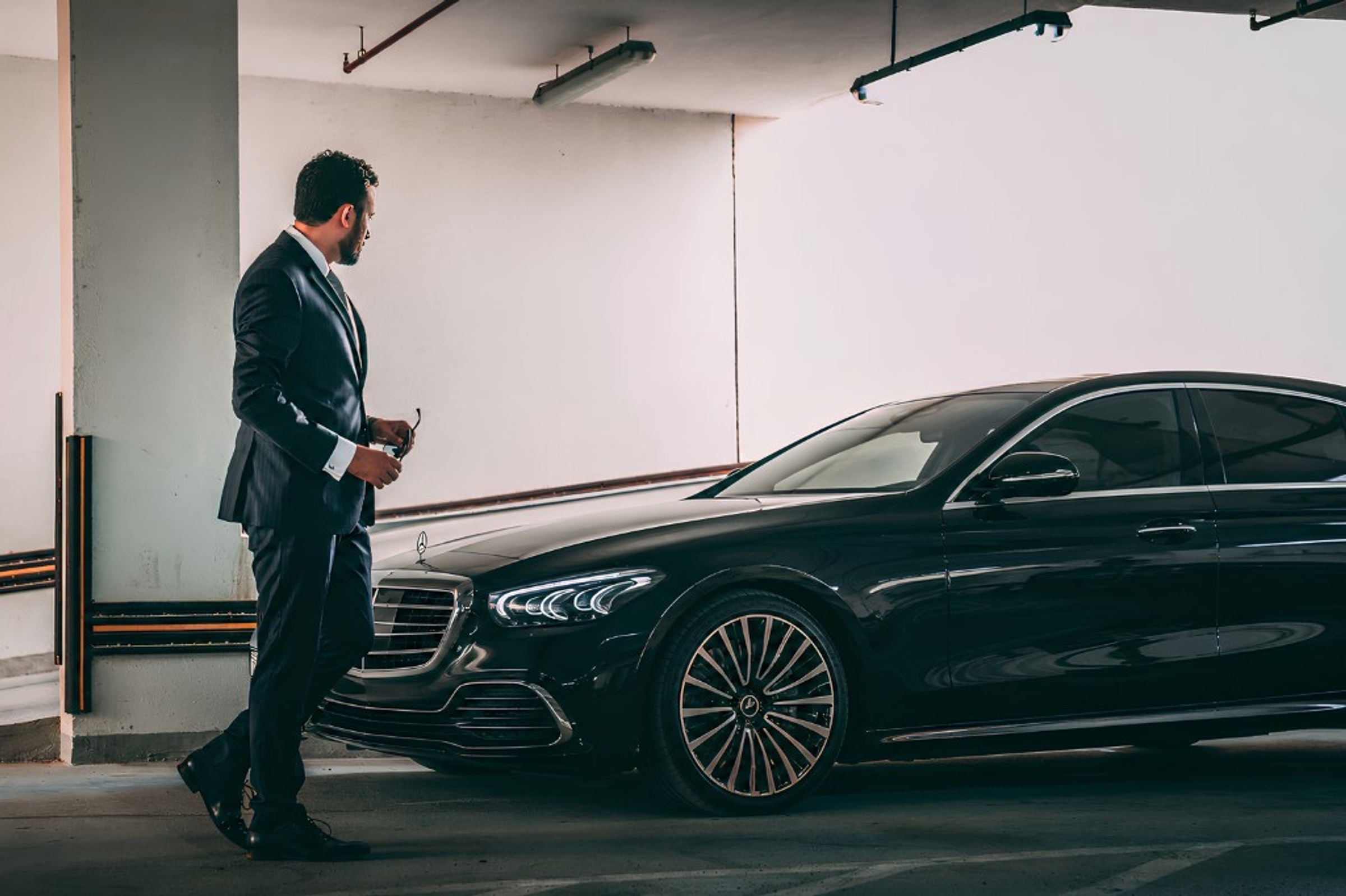 Chauffeur beside a black Mercedes-Benz S-Class in a private garage